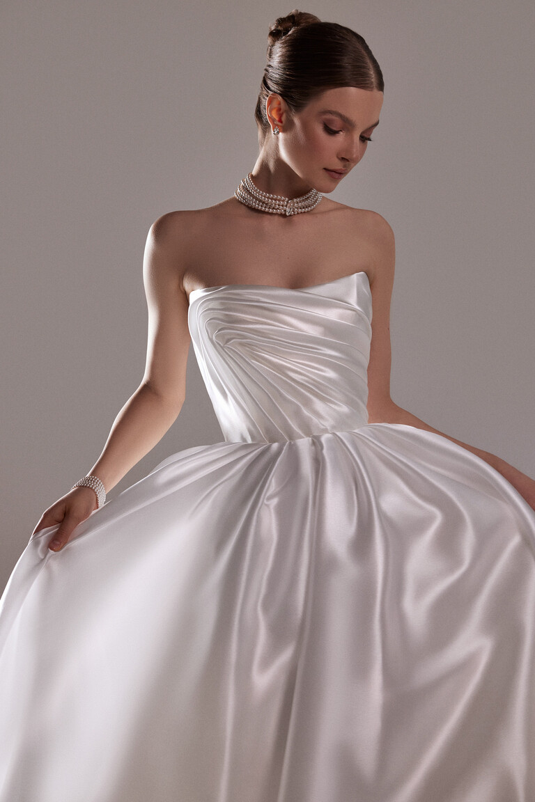 Stunning Nelly Off-White Bridal Gown Details Angled view of the Nelly minimalist off-white satin wedding dress featuring a draped bodice and voluminous skirt