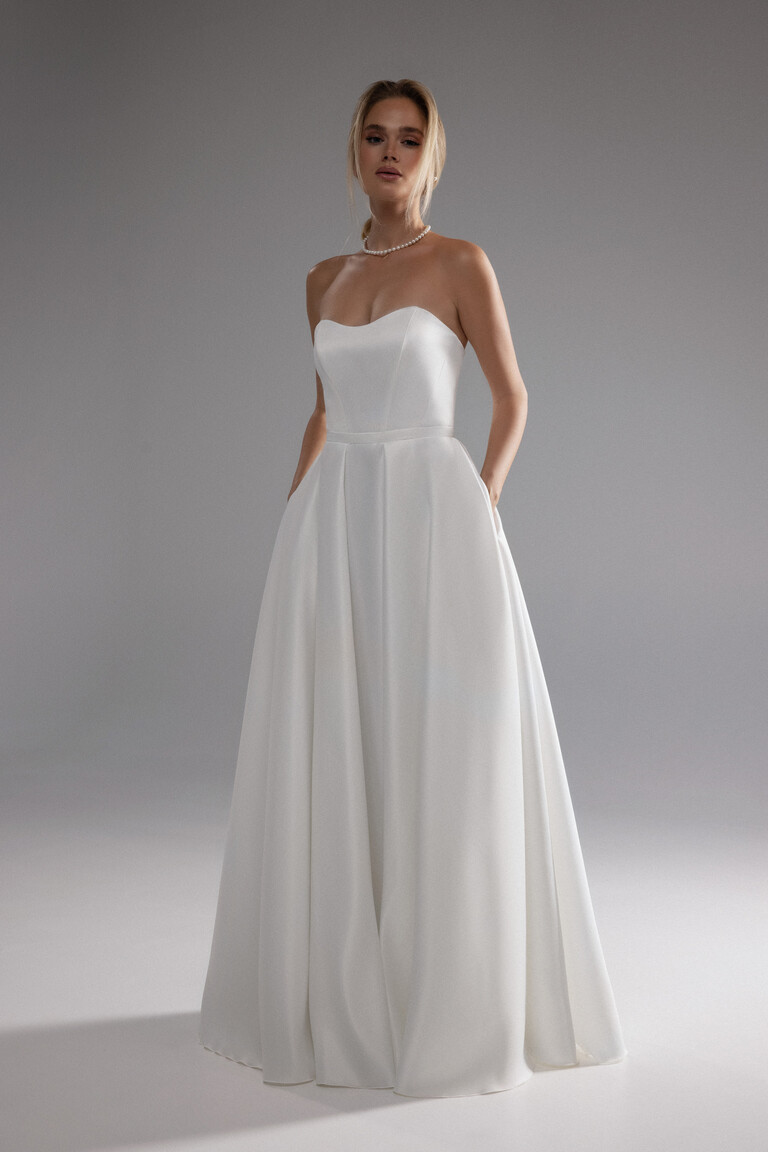 Modern Minimalist Lizzie Dress with Pockets Minimalist Lizzie ivory A-line bridal dress showing tailored strapless bodice and convenient side pockets.