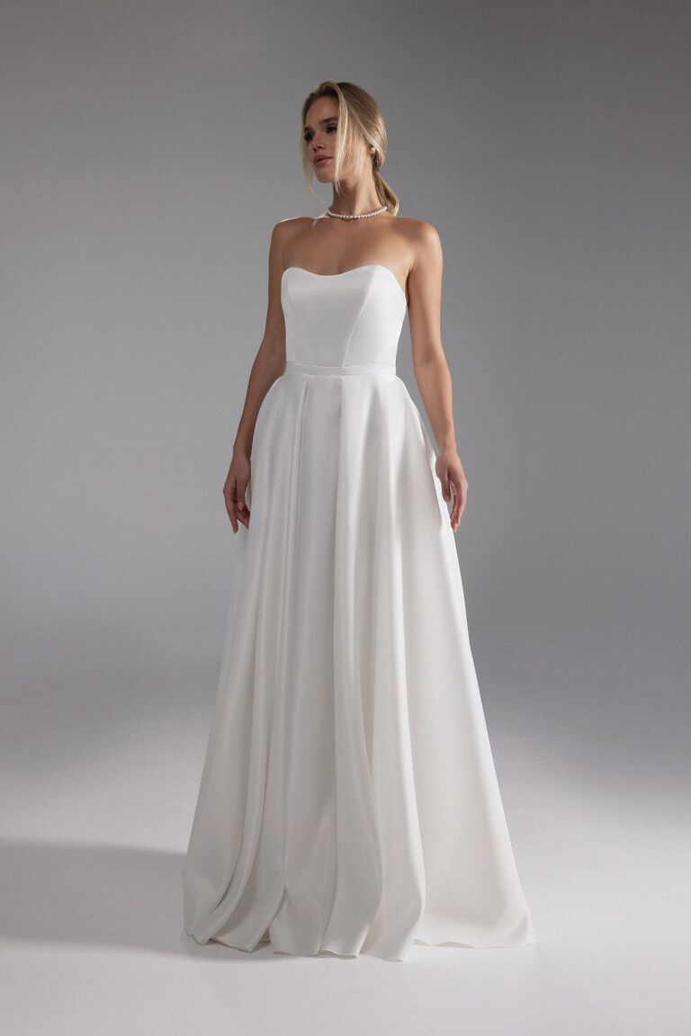 Full Body View of Lizzie Classic Wedding Dress Full-body front view of Lizzie ivory satin wedding dress with a strapless bodice and beautifully pleated floor-length skirt.