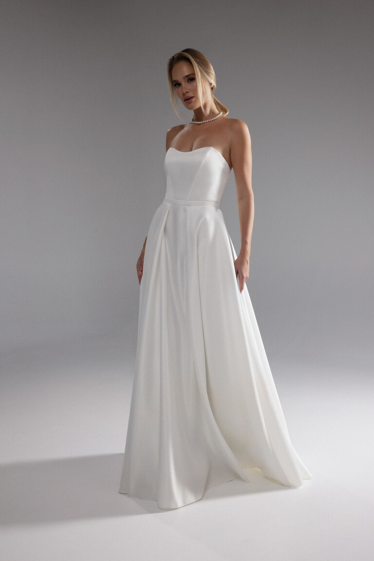 Minimalist A-Line Silhouette of Lizzie Dress Three-quarter view of the classic Lizzie ivory strapless wedding dress showcasing its minimalist satin A-line silhouette.