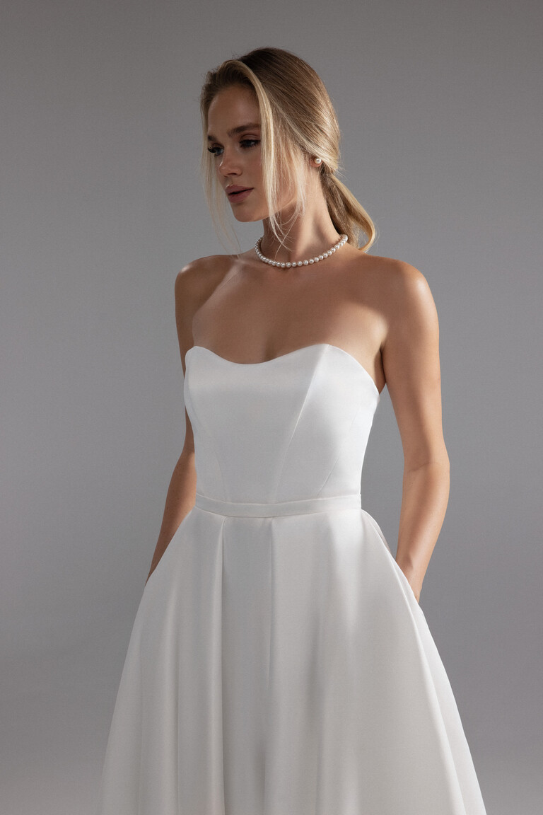 Classic Sweetheart Bodice Detail of Lizzie Gown Detail of the Lizzie ivory satin gown featuring a classic sweetheart neckline natural waist and discreet pockets.
