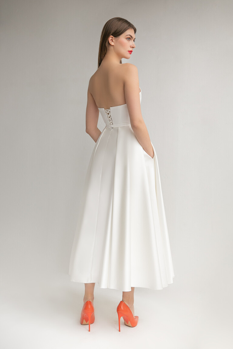 Three-quarter back view of Lizzie ivory midi dress showcasing the lace-up corset and side pockets.