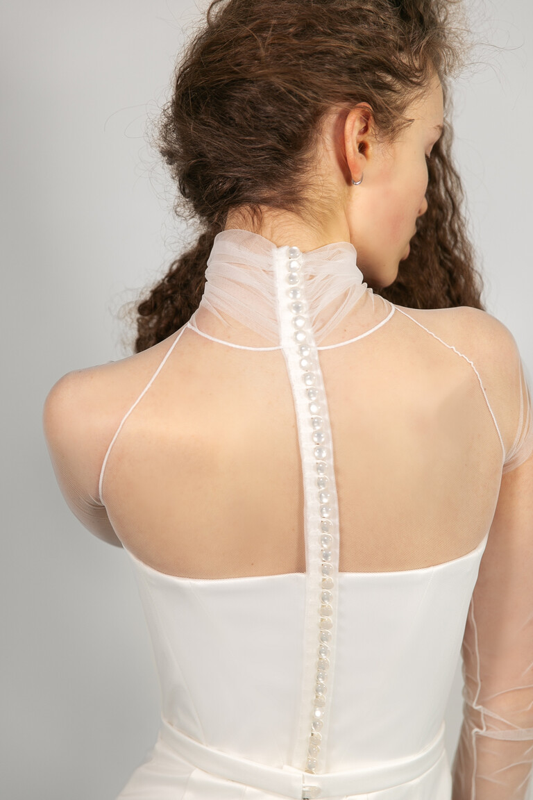 Delicate Button Closure Detail on Liz Dress Close-up back detail of Liz ivory bridal gown by Unona. Highlights the sheer mesh fabric and delicate covered button closure.