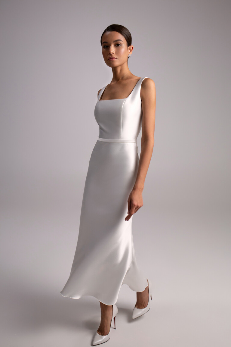 Elegant Mika Ivory Mikado Bridal Gown Angled front view of Mika sleeveless ivory bridal dress. Modern sheath midi gown featuring a fitted bodice and straps.