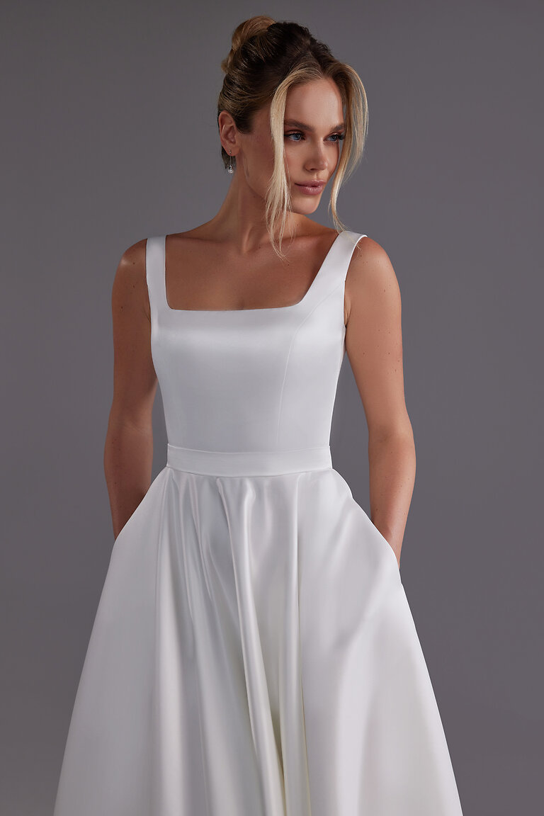 Modern Bridal Style Vlada Dress with Pockets Model wearing the Vlada midi off-white satin bridal dress with hands in the convenient side pockets by Unona