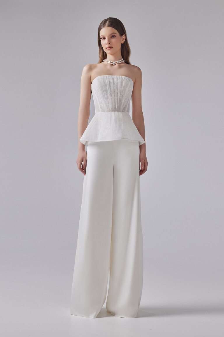 Front view of Unona Riki off-white bridal pantsuit with strapless lace peplum corset and wide-leg trousers