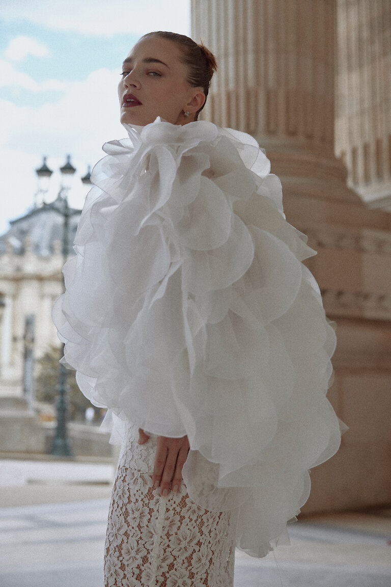 Sculptural Sheer Organza Bridal Wrap Side view of the Medea voluminous organza cape, a sculptural off-white bridal cover-up with overlapping sheer ruffles.