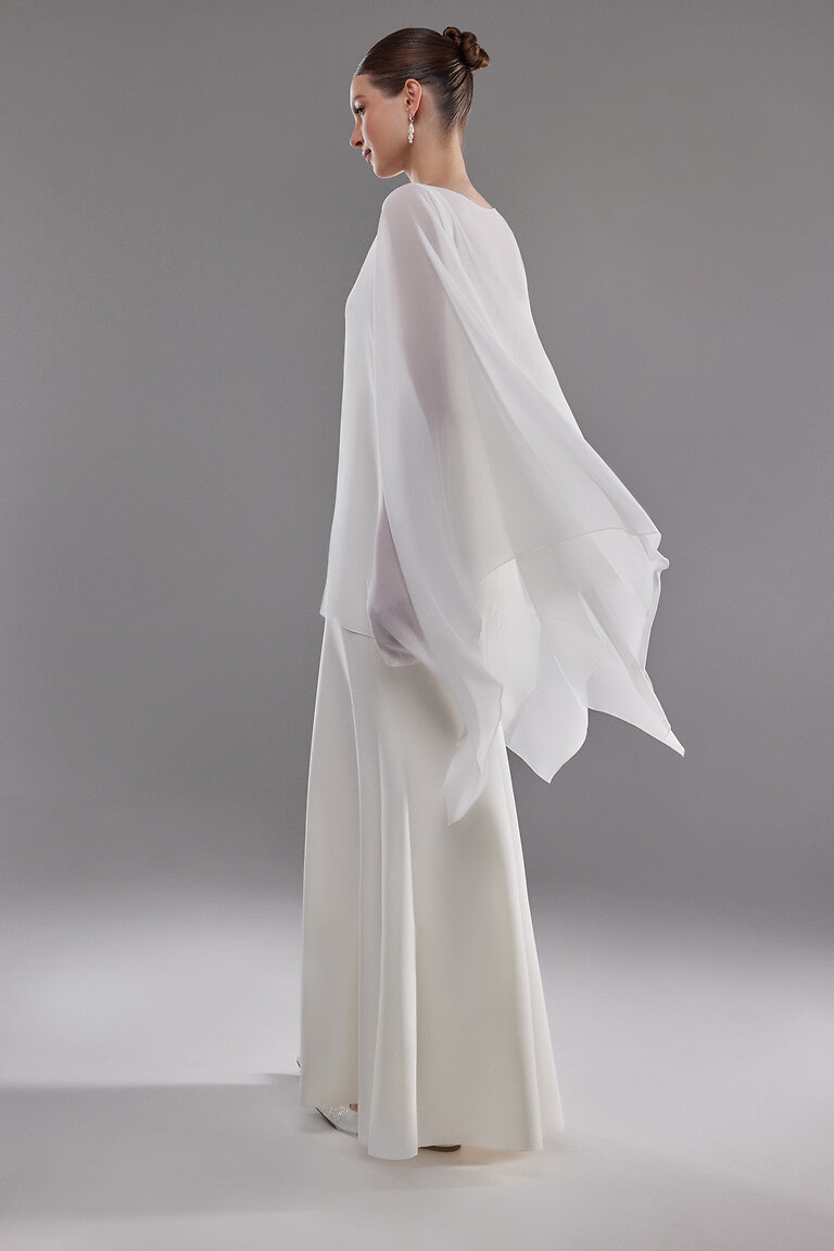 Flowing Chiffon Bridal Cape Side View Side view of the Iman white chiffon bridal cape highlighting the flowing drape and modest full back design.