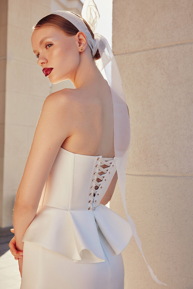 Traditional Lace-Up Back on Gina Corset Back view of Gina bridal corset showing traditional lace-up closure with metallic eyelets and ivory peplum waist.