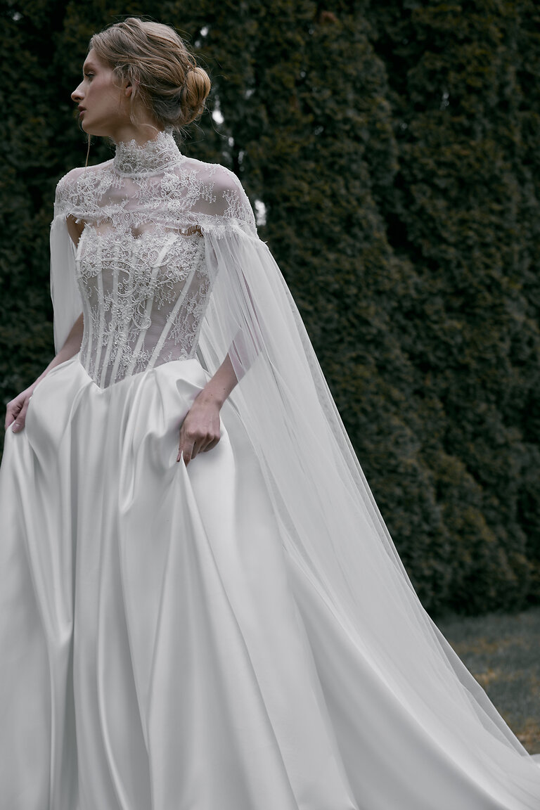 Romantic High Neck Lace Bridal Cape Evelyn Front side view of Evelyn high neck lace bridal cape in off-white tulle flowing elegantly over a corset gown.