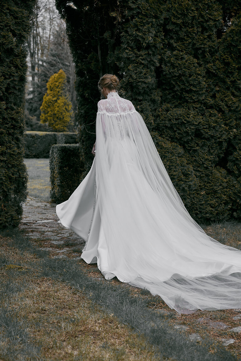Dramatic Tulle Chapel Train Wedding Cape Full length back view of the Evelyn off-white bridal cape featuring a dramatic tulle chapel train and lace back.