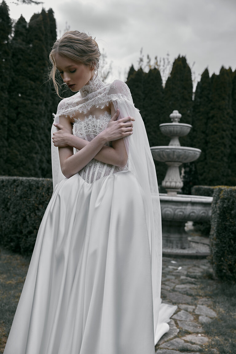 Off-White Tulle Wedding Cape with Lace Details Front view of the Evelyn off-white tulle wedding cape featuring a high lace neckline styled with a classic bridal gown.