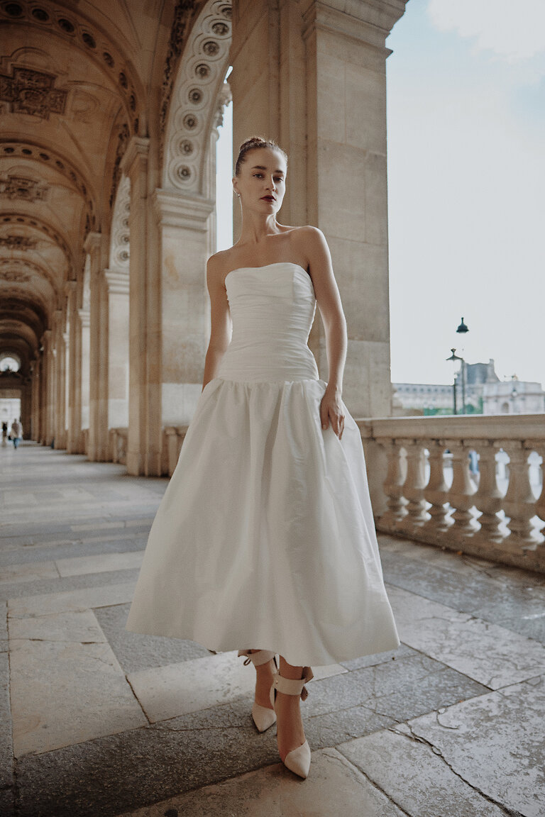 Louise Strapless Midi Bridal Gown Front View Unona Louise off-white strapless midi wedding dress with ruched bodice and drop waist. Full-length front view.
