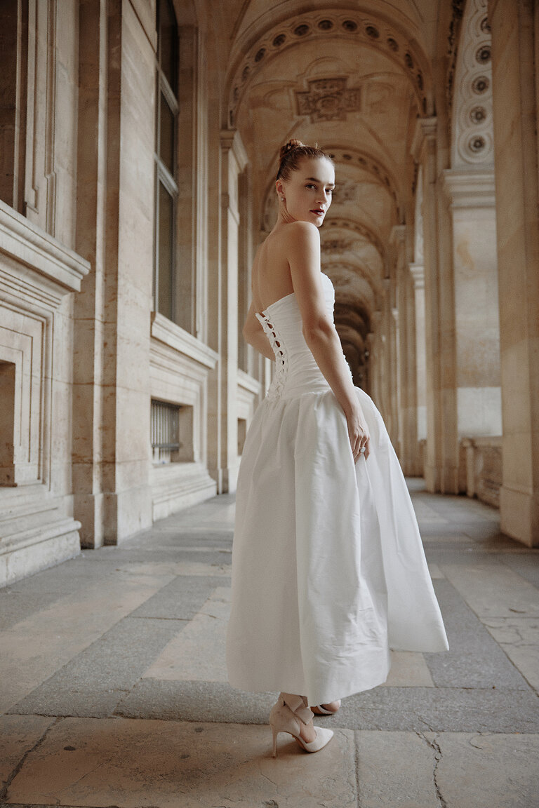 Louise Dress with Elegant Corset Back Detail Back view of Louise off-white A-line bridal gown showing corset lace-up details and voluminous midi skirt.