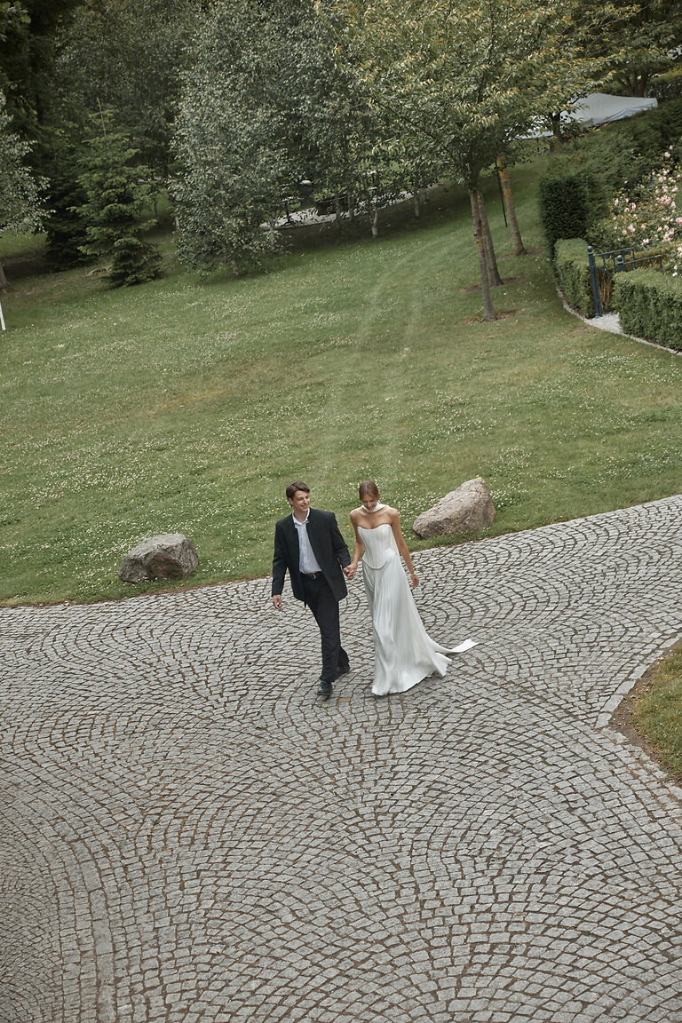 Ellora Drop Waist Silk Wedding Dress Bride walking in Ellora off-white drop waist wedding dress with pleated silk skirt and small train.