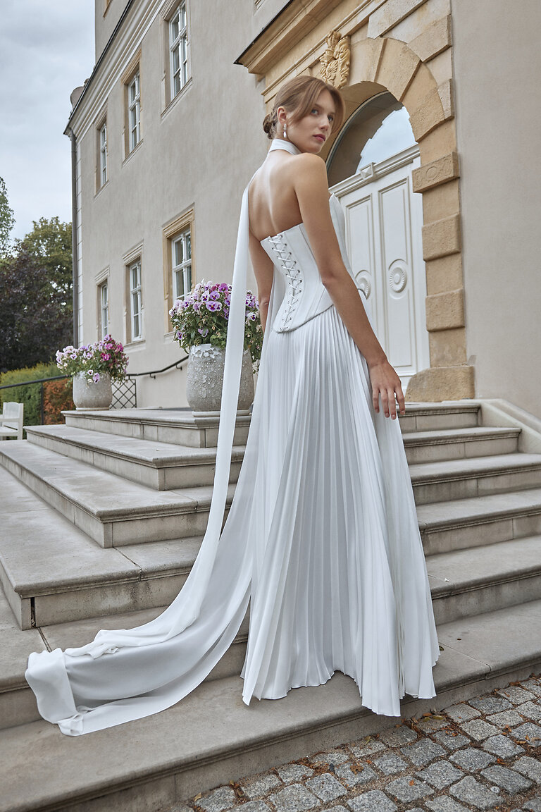 Ellora Lace-Up Back Corset Wedding Dress Back view of Ellora off-white wedding dress showing classic lace-up corset and flowing pleated silk skirt.