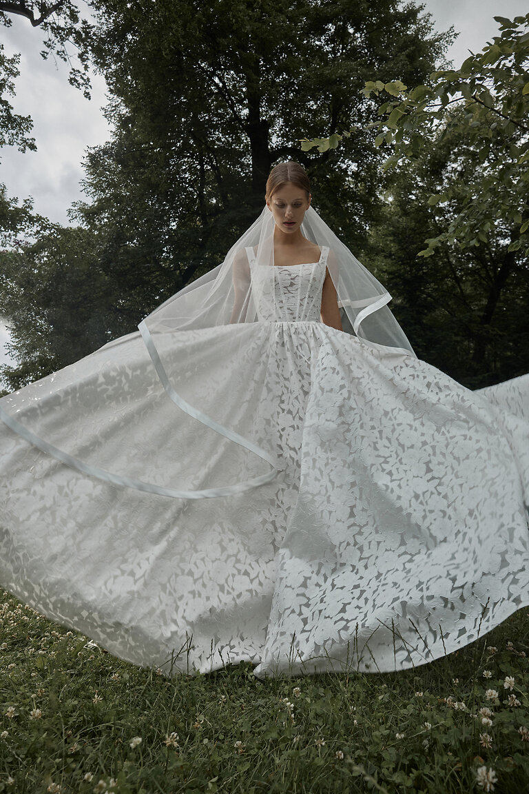 Dramatic Silhouette of Ruta Lace Bridal Gown Low-angle front view of Ruta off-white A-line lace wedding dress with expansive full skirt